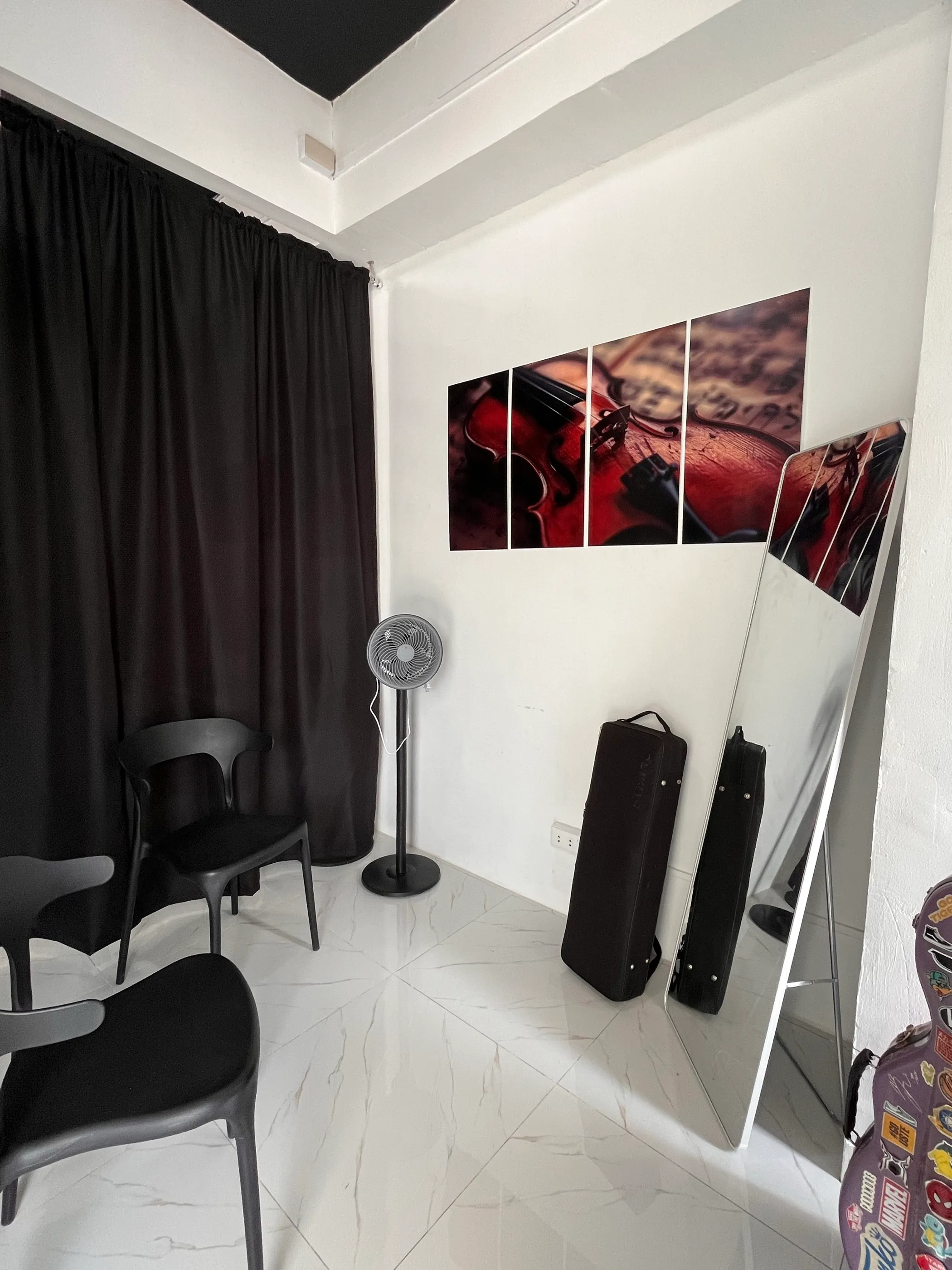 The violin studio, with a chair, case, and a close study of a violin on the wall